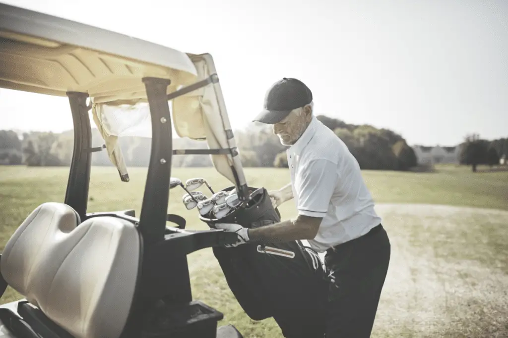 senior golfer loading a golf cart bag onto cart