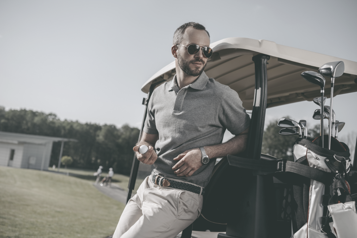 photo of man wearing sunglasses leaning on golf cart