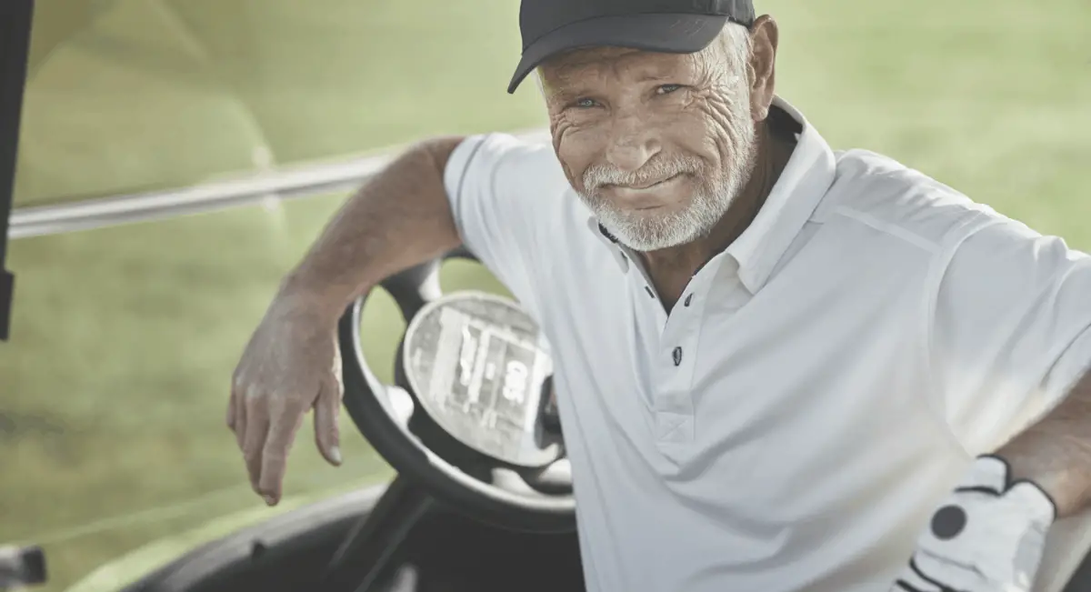 senior golfer sitting in golf cart smiling