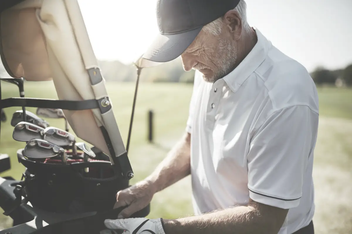 senior golfer with golf clubs on a cart
