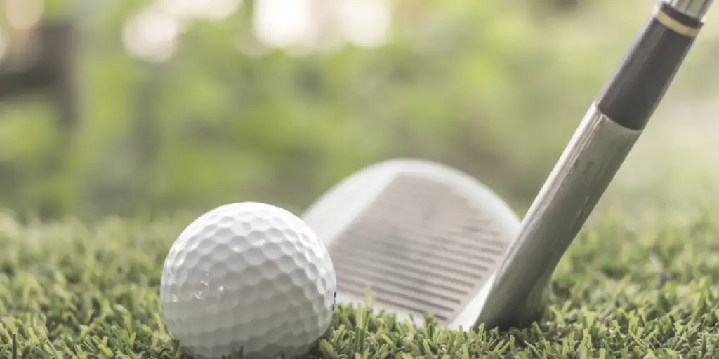 golf club wedge sitting behind ball in fairway