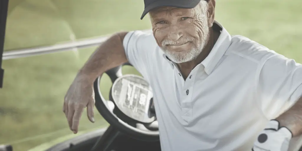 senior golfer sitting in golf cart smiling