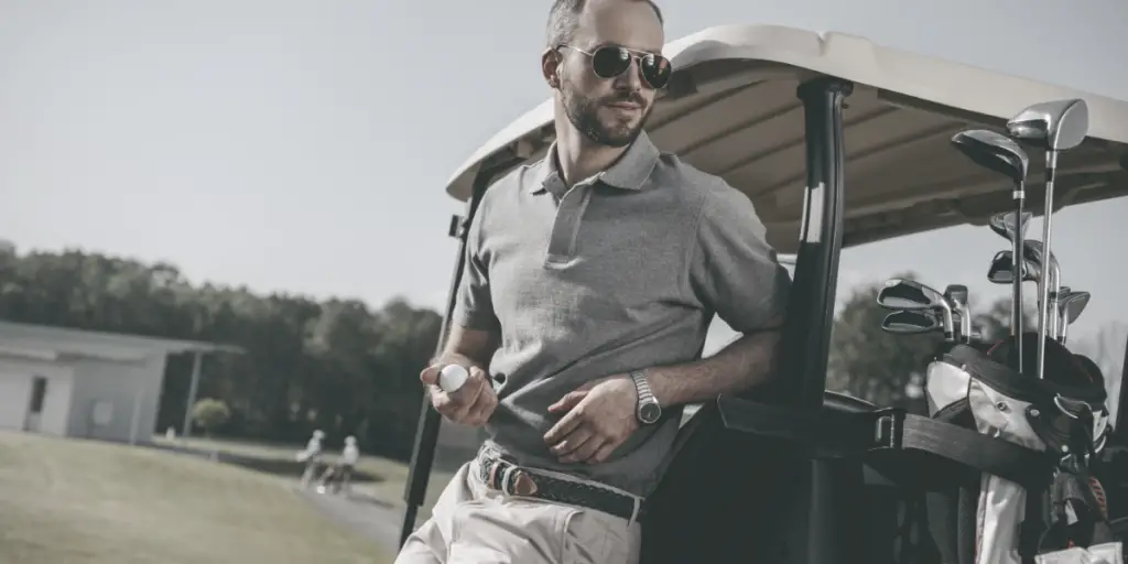 photo of man wearing sunglasses leaning on golf cart