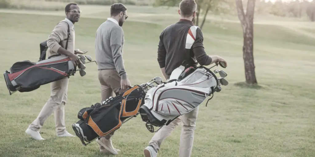 group of the 3 male golfers carrying golf bags